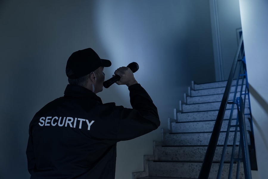 A security guard with a flashlamp at night