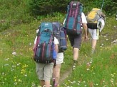 Three men backpacking along a trail away from the camera