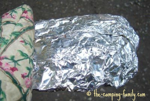 holding foil dinner with oven mitt