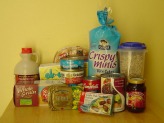 Food supplies stacked up on a brown table against a yellow wall.