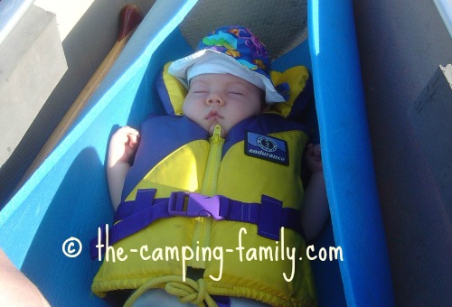 baby in life jacket sleeping on foam pad in canoe