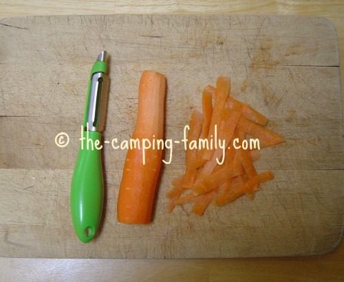 vegetable peeler, carrot, carrot strips on cutting board