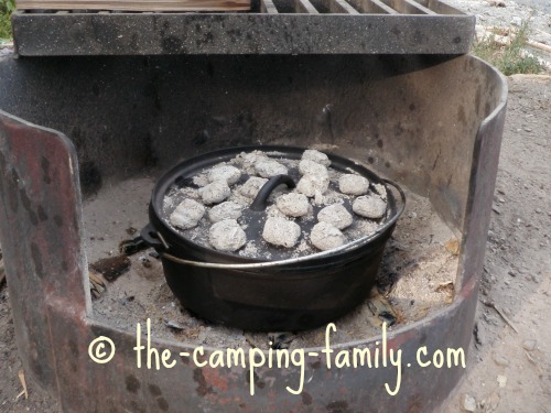 Dutch oven in fire pit with coals on lid