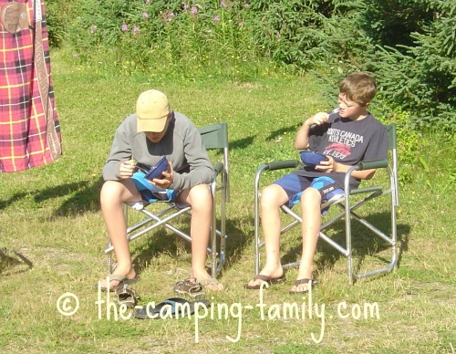 A man and a boy sitting in camping chairs with a table