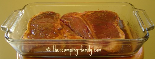 steak marinating in a glass pan