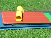 Three colored sleeping pads stacked up on grass