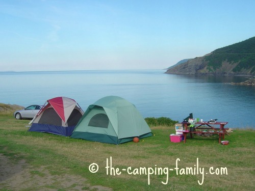 Two tents at the edge of the water by a lake.