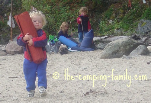 A toddler carrying a Thermarest pad