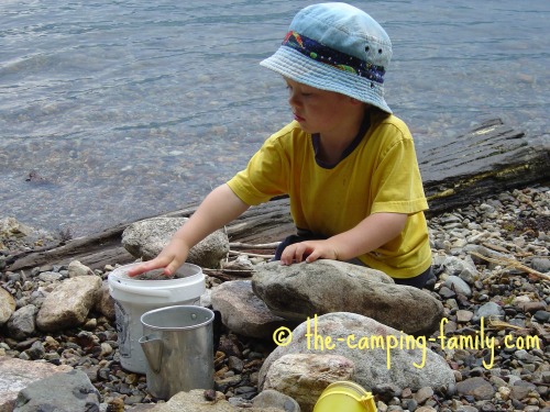 small boy playing with rocks and a bucket