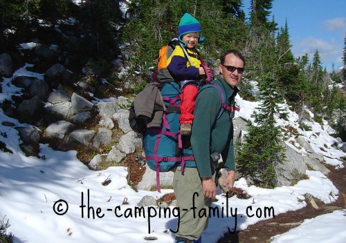 child riding on top of dad's backpack