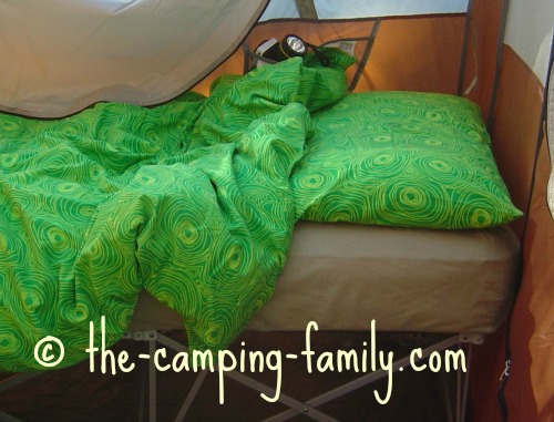 camping cot with pillow and duvet, in tent